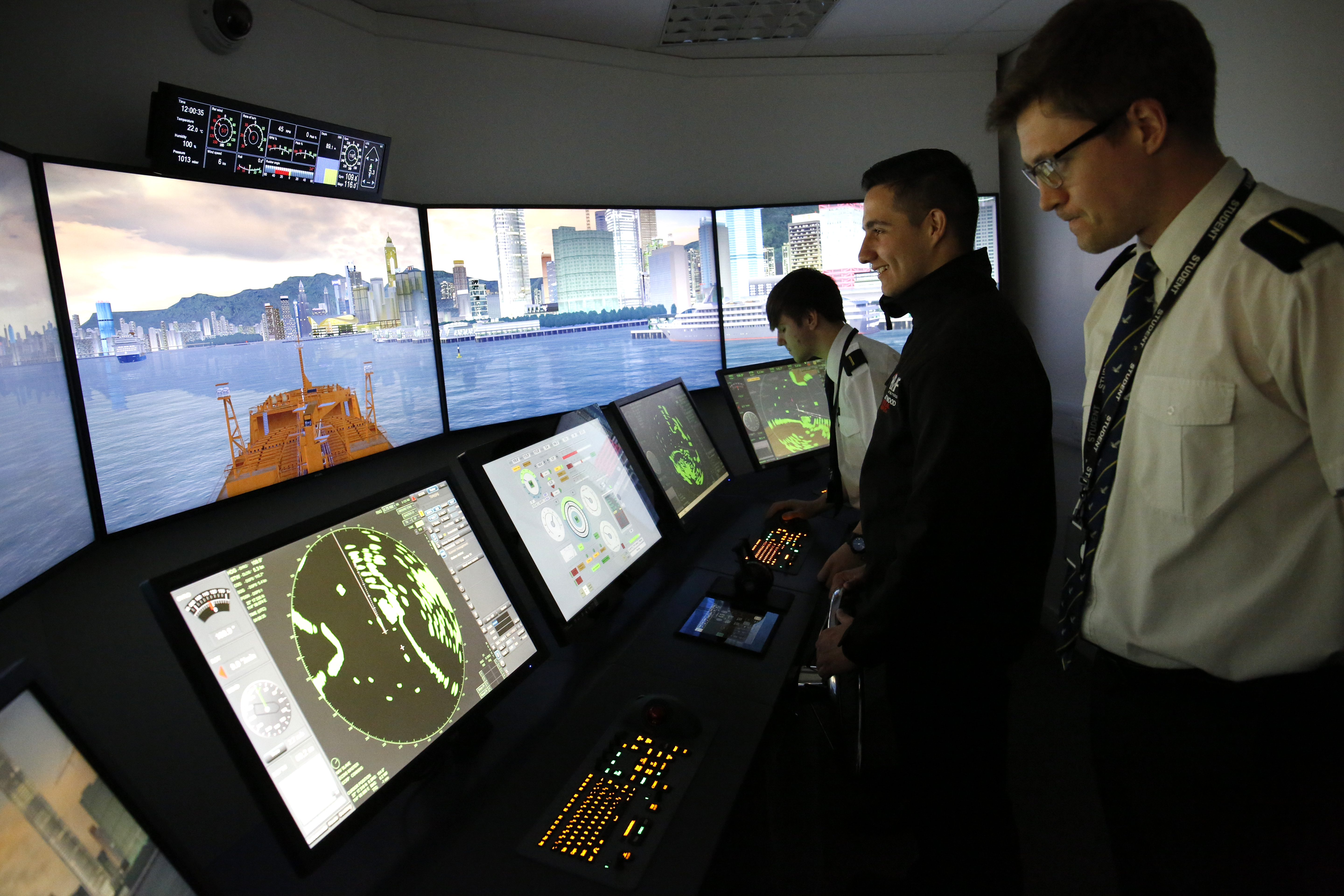 Image showing three students standing inside the full-size bridge simulator at Fleetwood campus